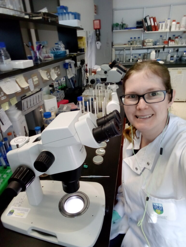 Karen smiling sitting by a microscope.